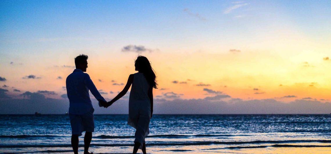 A couple taking a walk by the sea.